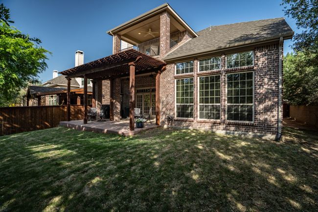 A covered patio overlooks the tranquil, shaded back yard. | Image 9