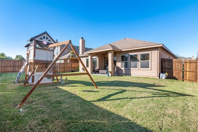 Rear view of house with a patio area, a playground, a lawn, and a fenced backyard | Image 26