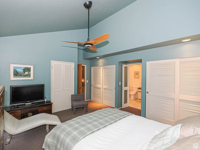 Carpeted bedroom with multiple closets, high vaulted ceiling, ceiling fan, and ensuite bath | Image 27