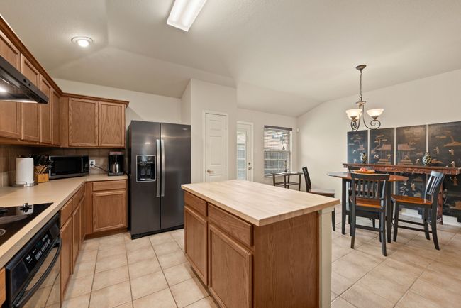 Sink and countertop space with open views into the fireplace-lit living area and entry. | Image 19