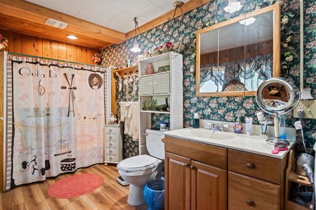 Bathroom with wallpapered walls, vanity, and wood finished floors | Image 24