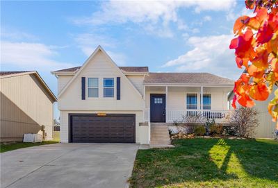 View of front of property featuring covered porch, a garage, and a front lawn | Image 1