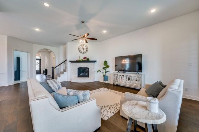 Living room with arched walkways, a ceiling fan, recessed lighting, a fireplace, and dark wood-type flooring | Image 6