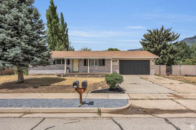 Single story home featuring driveway, an attached garage, a porch, brick siding, and fence | Image 5