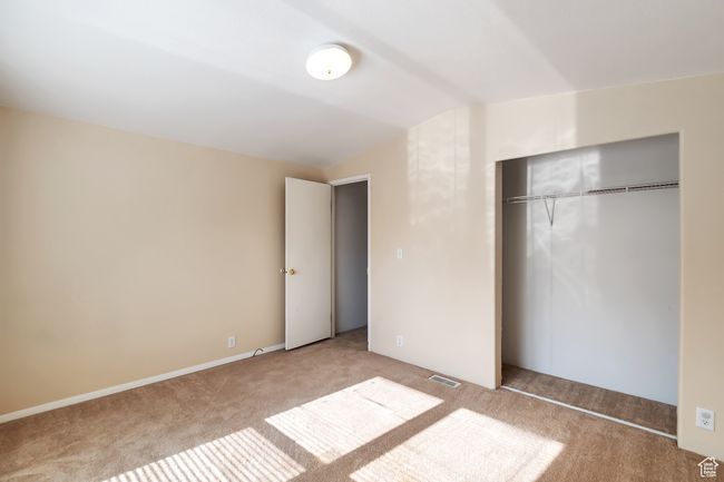 Unfurnished bedroom with carpet floors, lofted ceiling, and a closet | Image 17