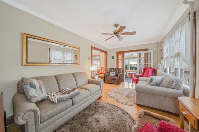Living room featuring a ceiling fan, wood finished floors, and crown molding | Image 7
