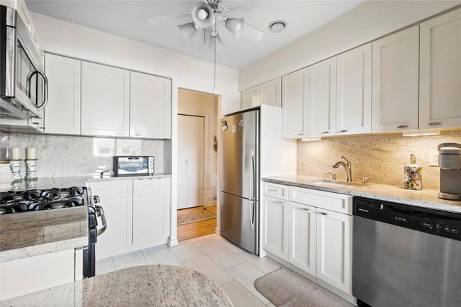 Kitchen with stainless steel appliances, a sink, a ceiling fan, and white cabinetry | Image 9
