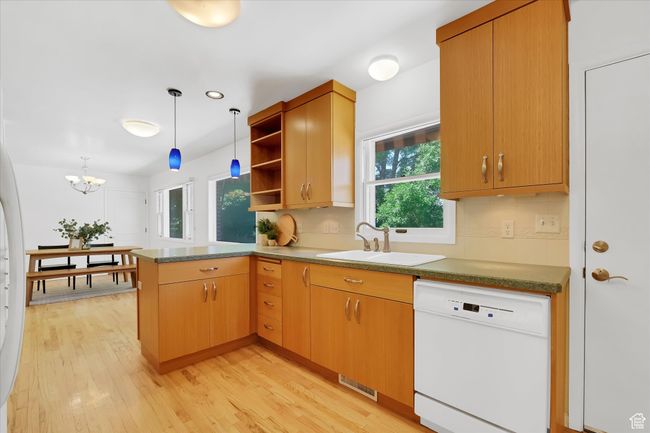 Kitchen with white dishwasher, a peninsula, open shelves, light wood finished floors, and hanging light fixtures | Image 8