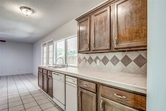 Kitchen featuring dishwasher, a sink, decorative backsplash, tile counters, and light tile patterned floors | Image 13