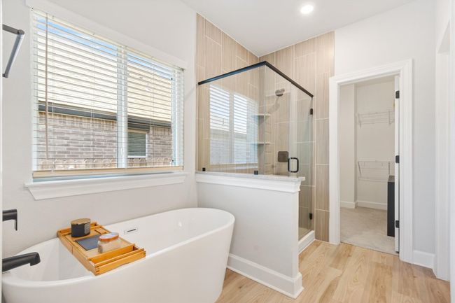 Full bathroom with a stall shower, a walk in closet, wood finished floors, and a freestanding bath | Image 15