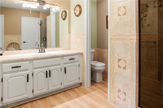 Bathroom featuring a wainscoted wall, wood finished floors, toilet, tile walls, and a stall shower | Image 22