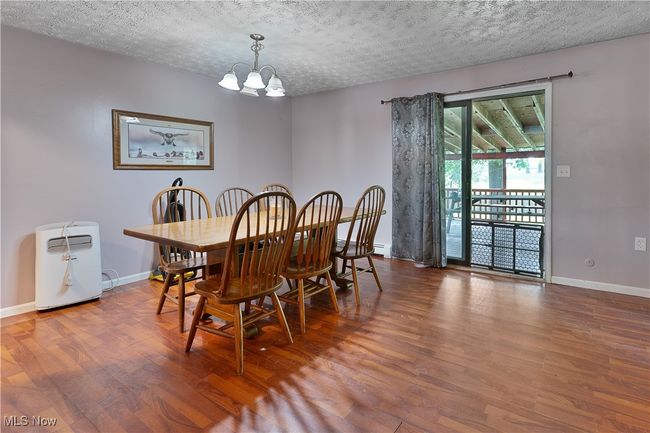 Dining space featuring a chandelier, wood finished floors, a textured ceiling, and a baseboard heating unit | Image 11