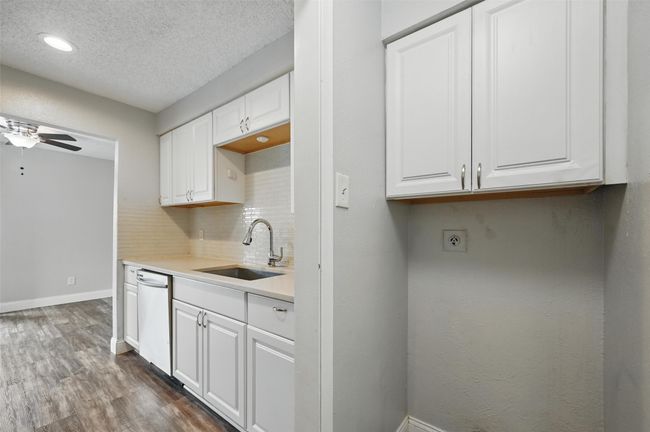 Kitchen with dishwasher, white cabinets, dark wood finished floors, tasteful backsplash, and light countertops | Image 10