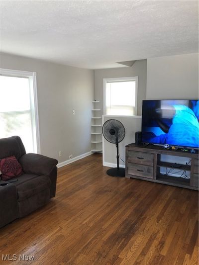 Living room with dark wood-type flooring and a textured ceiling | Image 3