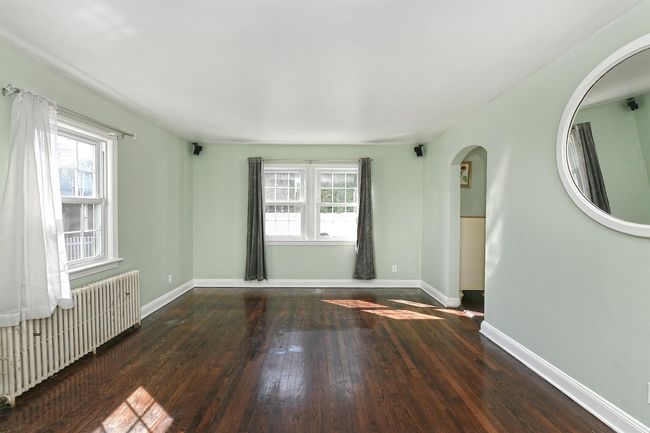 Unfurnished room with baseboards, arched walkways, radiator heating unit, and wood-type flooring | Image 6