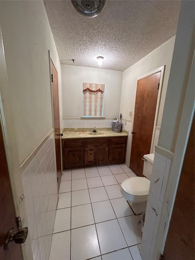 Bathroom featuring a wainscoted wall, tile patterned flooring, tile walls, and a textured ceiling | Image 17