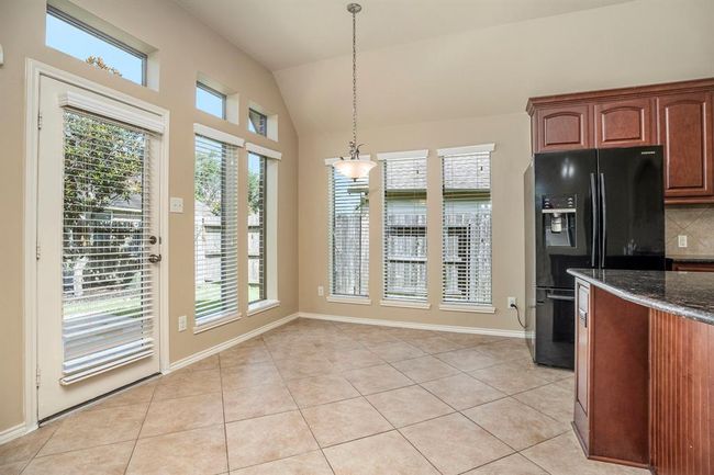 Surrounded by windows, the breakfast area offers a sunny spot to start your day. The space is open and cheerful, with backyard views and easy access through the nearby patio door—ideal for enjoying your morning coffee or casual meals. | Image 15