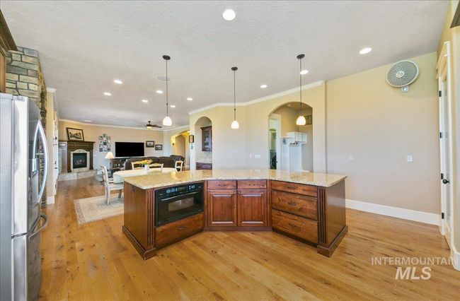 Kitchen featuring stainless steel refrigerator with ice dispenser, arched walkways, a center island, light wood finished floors, and recessed lighting | Image 14