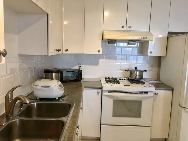 Kitchen with white cabinets, a sink, gas range gas stove, backsplash, and under cabinet range hood | Image 9