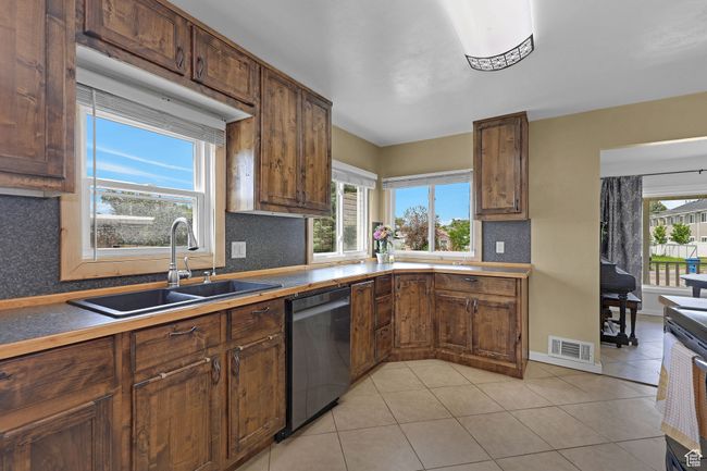 Kitchen featuring dishwashing machine, a sink, backsplash, and light tile patterned floors | Image 14