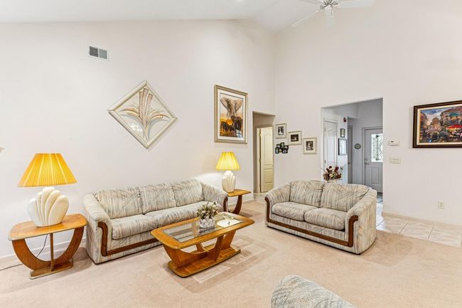 Living room with high vaulted ceiling, visible vents, carpet, ceiling fan, and tile patterned floors | Image 14