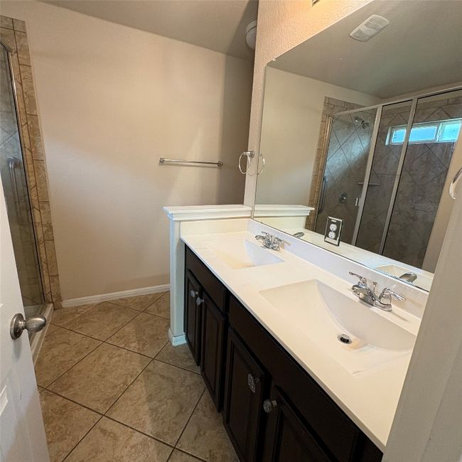 Full bathroom featuring a stall shower, double vanity, and light tile patterned floors | Image 9