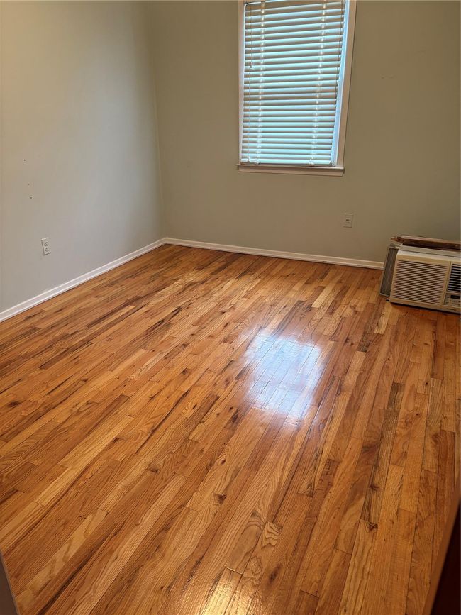 Empty room with a wall unit AC, hardwood / wood-style flooring, and baseboards | Image 8