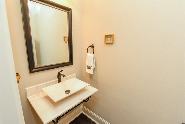 The guest half bath has wood floors, a stone basin with wrought iron wall bracket. The 6" base boards and crown molding are even featured here! | Image 12