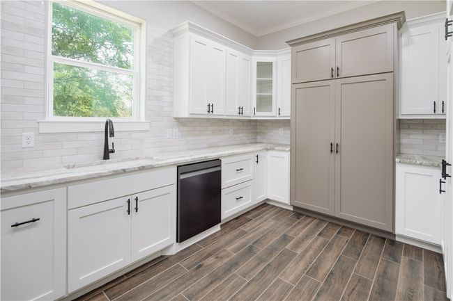 Kitchen with stainless steel dishwasher, backsplash, glass insert cabinets, ornamental molding, and dark wood-style floors | Image 6