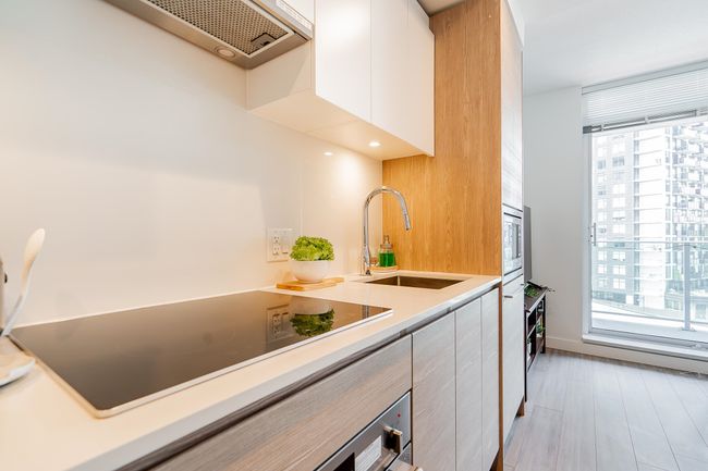 Kitchen featuring a wealth of natural light, stainless steel microwave, black electric stovetop, and a sink | Image 6