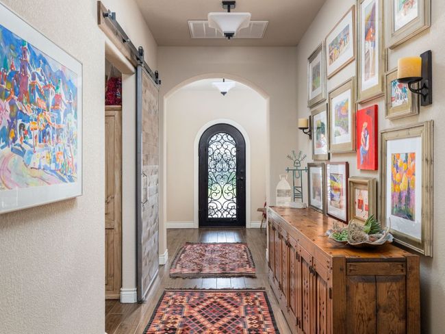 Stunning iron front door, art display wall, barn door is entry to art room / study | Image 4