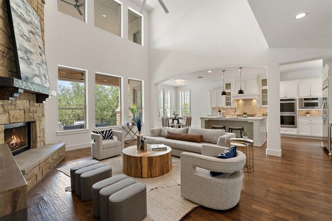 Living room with a towering ceiling, dark wood-style flooring, a fireplace, arched walkways, and recessed lighting | Image 16