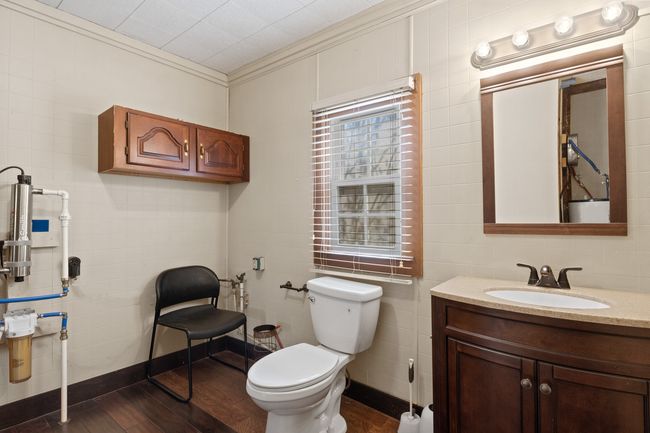 Bathroom featuring hardwood / wood-style floors, tile walls, toilet, vanity, and crown molding | Image 17