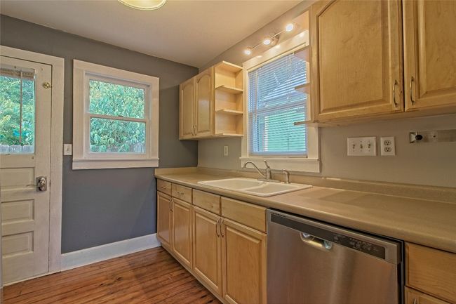 Kitchen featuring stainless steel dishwasher, light brown cabinetry, and light wood-style flooring | Image 14