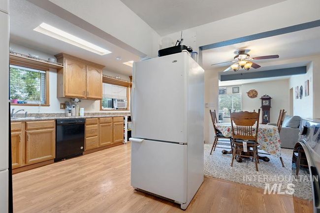 Kitchen featuring freestanding refrigerator, dishwasher, light wood-type flooring, light brown cabinets, and ceiling fan | Image 16