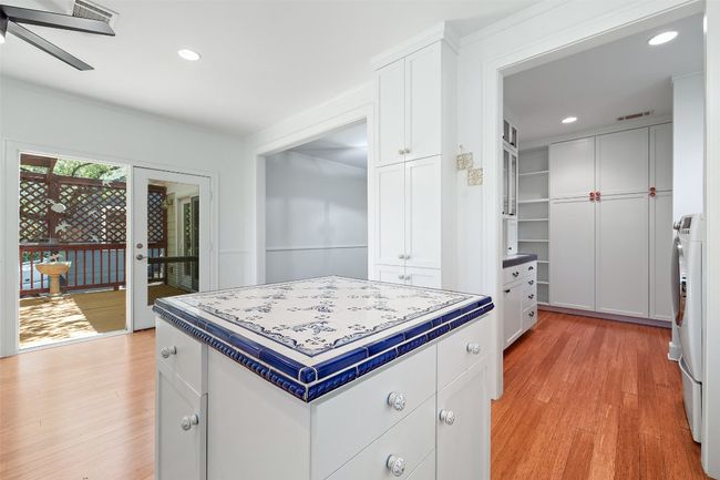 Kitchen with tile countertops, light wood-type flooring, a ceiling fan, white cabinets, and recessed lighting | Image 11