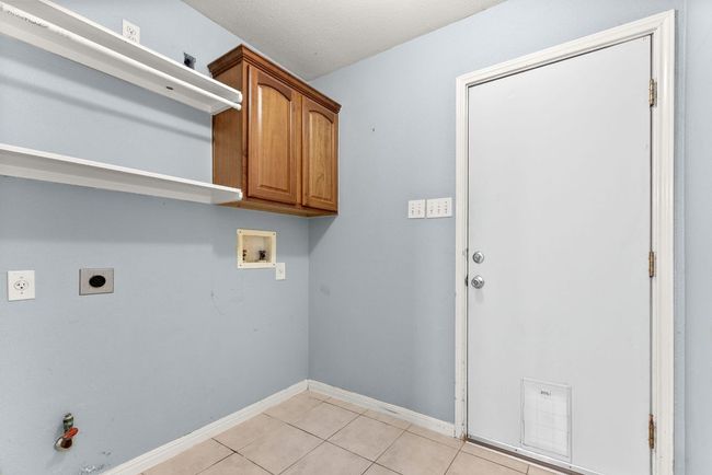 Laundry area featuring cabinet space, hookup for a washing machine, electric dryer hookup, baseboards, and light tile patterned floors | Image 27