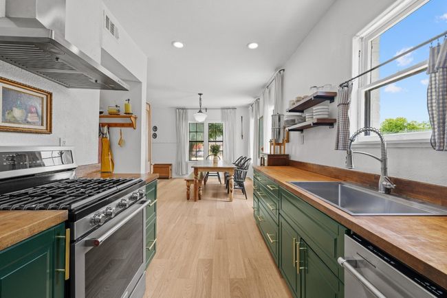 Kitchen with green cabinetry, stainless steel appliances, range hood, butcher block countertops, and recessed lighting | Image 11