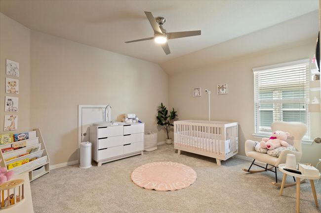 Bedroom featuring a nursery area, carpet floors, vaulted ceiling, baseboards, and ceiling fan | Image 25