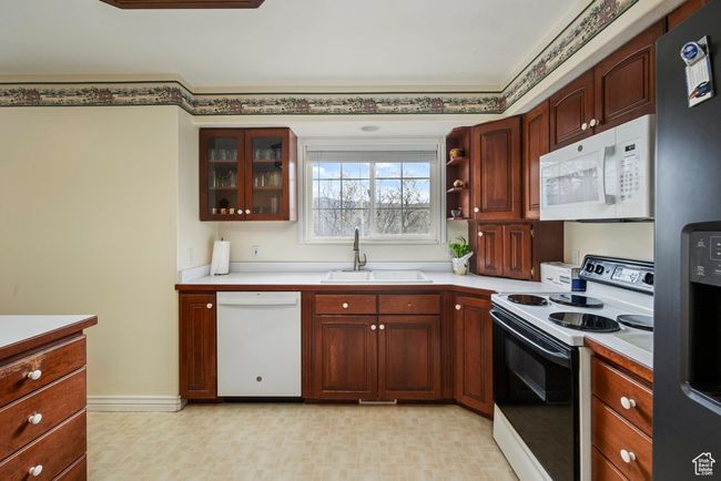 Kitchen with a sink, white appliances, and light countertops | Image 20