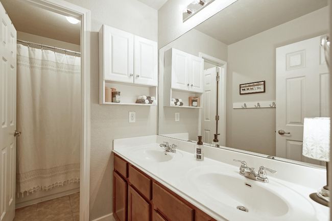 Dual vanities, tile flooring, and a bathtub/shower combo in this full bathroom. | Image 24