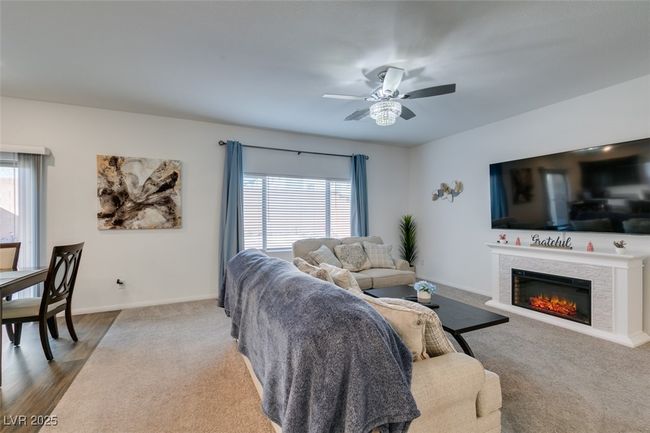Living area featuring baseboards, a lit fireplace, dark wood-type flooring, and ceiling fan | Image 13