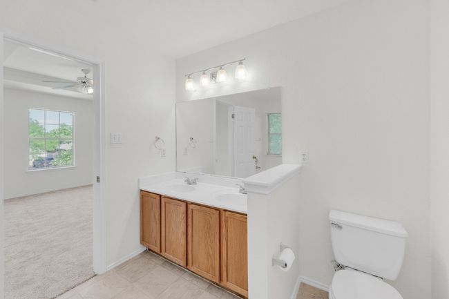 Full bath with double vanity, toilet, a ceiling fan, a sink, and baseboards | Image 19