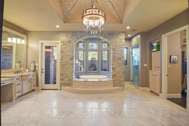 The spa-like primary bathroom has a raised jetted tub with views of the courtyard and fountain | Image 25