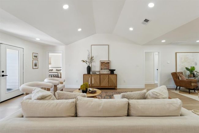Elegant French doors anchors the far wall, offering picturesque views of the lush backyard and inviting in sunlight throughout the day. | Image 6