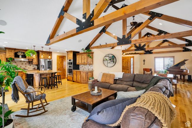 Living room with vaulted ceiling with beams, light wood-style flooring, and a ceiling fan | Image 10