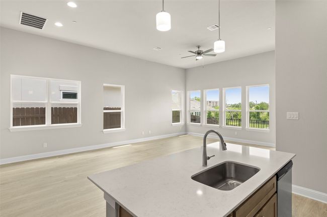Kitchen featuring a sink, open floor plan, stainless steel dishwasher, decorative light fixtures, and a ceiling fan | Image 21