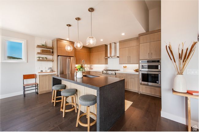 Kitchen with dark hardwood / wood-style floors, wall chimney range hood, stainless steel appliances, and hanging light fixtures | Image 6