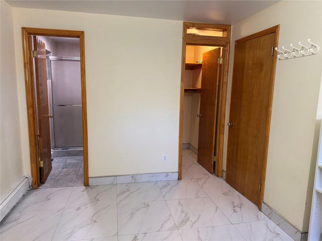 Unfurnished bedroom with baseboard heating, marble finish floor, and baseboards | Image 16