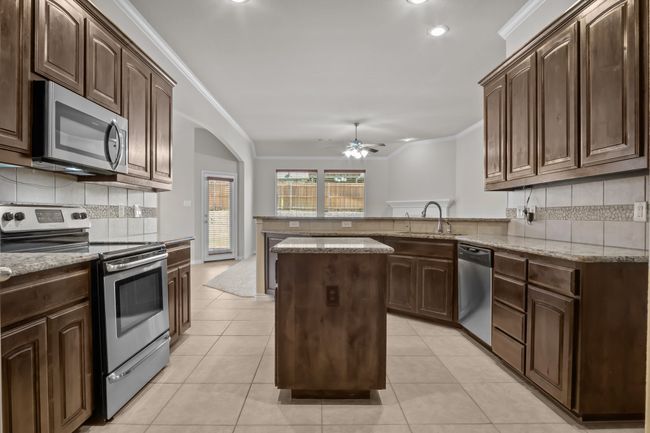 Kitchen featuring ceiling fan, crown molding, a sink, a peninsula, and stainless steel appliances | Image 7